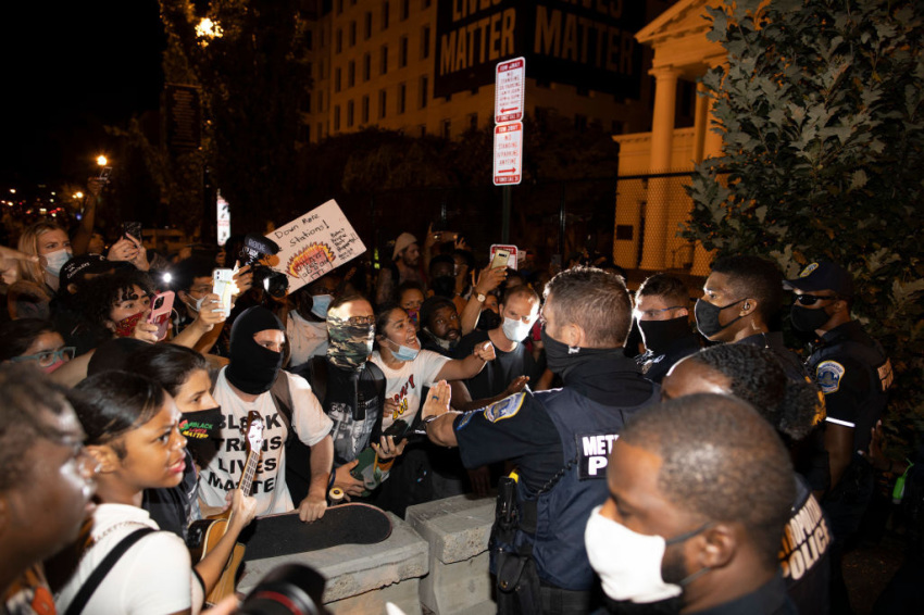 Washington D.C. Police try to keep demonstrators back as they gather at Black Lives Matter plaza on August 27, 2020, in Washington, D.C. Protesters gathered on the final night of the Republican National Convention in which both President Donald Trump Vice President Mike Pence accepted the Republican nomination as candidates for a second term. One demonstrator is seen wearing a Black Trans Lives Matter T-shirt and another in the background is holding a sign saying "Burn Down the Police Station."
