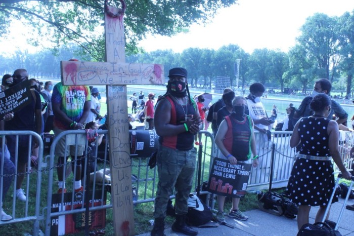 Denorver Garrett stands by his cross at the Get Your Knee Off Our Neck Commitment March in Washington D.C. on Aug. 28, 2020. 