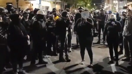An activist speaks through a megaphone in the streets of Portland, Oregon after the killing of Aaron Danielson on Aug. 29, 2020.