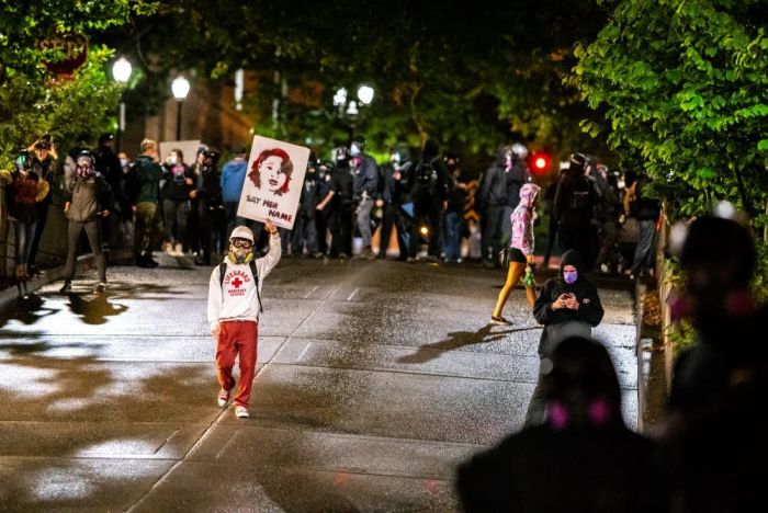 A protester walks toward Portland police with a sign honoring Breonna Taylor on September 23, 2020, in Portland, Oregon. Violent protests erupted across the nation Wednesday following the results of a grand jury investigation into the police shooting death of Taylor. (Photo by Nathan Howard/Getty Images)