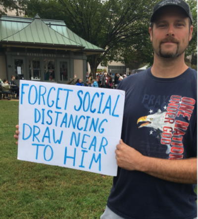 An attendee of 'The Return' event in Washington, D.C. holds a sign reading 'Forget social distancing. Draw near to Him,' Sept. 26, 2020.