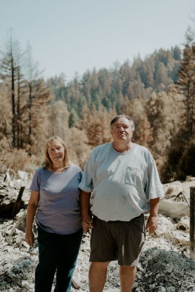 Dan and Rochelle Kelly pose of a photograph in front of the remains of their home in Boulder Creek, California, in September 2020. 