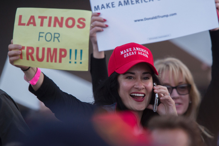 A woman holds a sign expressing Latino support for Republican presidential candidate Donald Trump at his campaign rally at the Orange County Fair and Event Center, April 28, 2016, in Costa Mesa, California. 