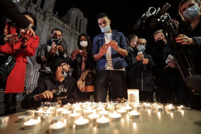 People lights candle outside the Notre-Dame de l'Assomption Basilica in Nice on October 29, 2020, in tribute to the three victims of a knife attacker inside the church of the French Riviera city.