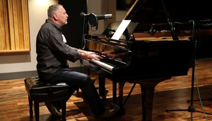 Dennis Jernigan at the piano, where he's written hundreds of published worship songs. At 61, Jernigan is dealing with a damaged left vocal cord and early stage Parkinson's disease, but he is taking to social media to amplify, not stop, his ministry.