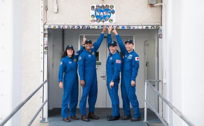 Crewmembers of the SpaceX Crew Dragon’s capsule Resilience point to a NASA sign before taking off for the International Space Station on Nov. 15, 2020. From right to left: Shannon Walker, Victor Glover, Michael Hopkins and Soichi Noguchi.