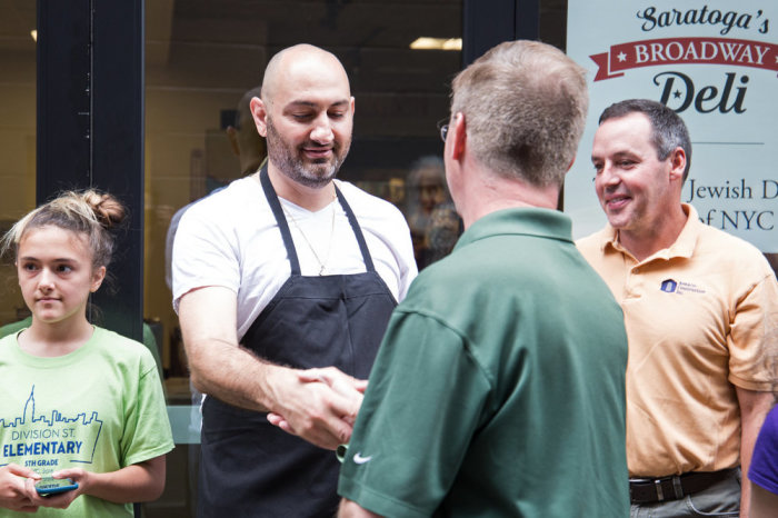 Saratoga’s Broadway Deli owner Daniel Chessare shakes hands at the grand opening of his business in Saratoga Springs, New York, in 2018.