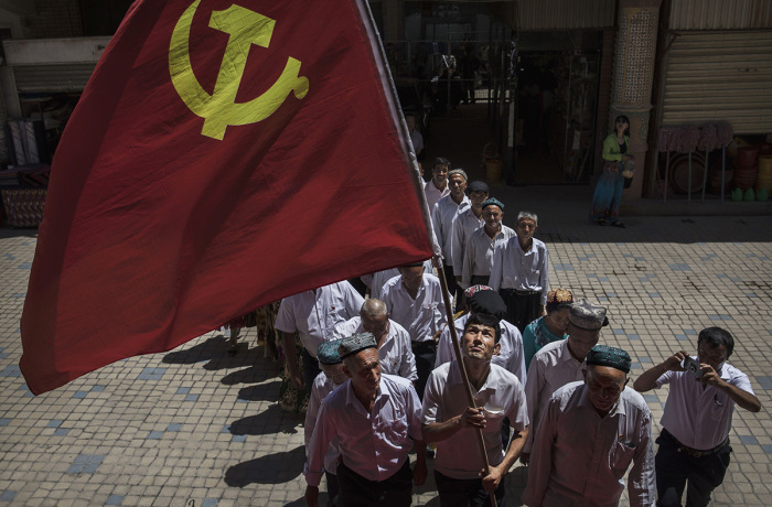 Ethnic Uyghur members of the Communist Party of China carry a flag as they take part in an organized tour on June 30, 2017, in the old town of Kashgar, in the far western Xinjiang province, China. 