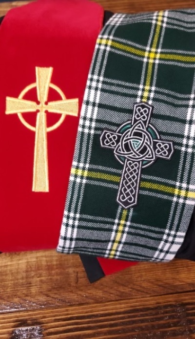 A red United Methodist stole and a stole with the Order of St. Patrick tartan and symbol. 