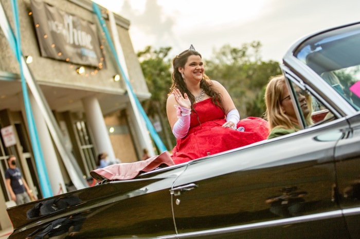 A prom queen waves from the back of a convertible during the Shine-Thru prom event. 