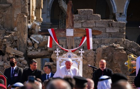 Pope Francis speaks while seated on the podium at the square near the ruins of the Syriac Catholic Church of the Immaculate Conception (al-Tahira-l-Kubra), in the old city of Iraq's northern Mosul on March 7, 2021.