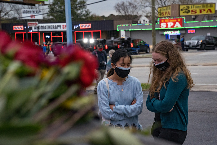 People bring flowers to the memorial site set up outside of The Gold Spa on March 19, 2021, in Atlanta, Georgia. Mourners have gathered to pay their respects after suspect Robert Aaron Long, 21, attacked three spas killing eight people, six of whom were Asian and two of whom were white. 