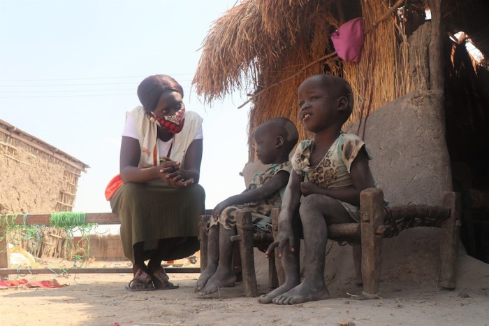 A World Vision employee talks to two children during a visit in South Sudan.