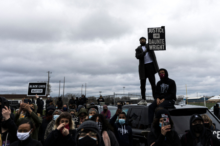 People gather holding signs and flags before curfew to protest the death of Daunte Wright who was shot and killed by a police officer in Brooklyn Center, Minnesota on April 12, 2021.