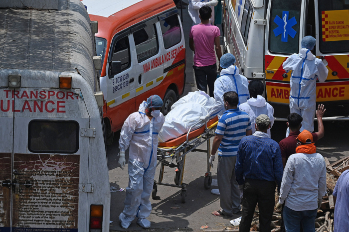 Family members and ambulance workers in PPE kits (Personal Protection Equipment) carry the bodies of victims who died of the COVID-19 coronavirus at a crematorium in New Delhi, India, on April 27, 2021. 