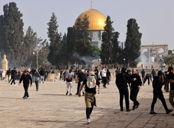 Palestinians run for cover from tear gas fired by Israeli security forces at Jerusalem's Al-Aqsa mosque compound on May 10, 2021, ahead of a planned march to commemorate Israel's takeover of Jerusalem in the 1967 Six-Day War. 