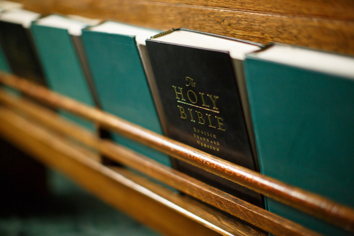 Bibles sit inside a church pew holder. 