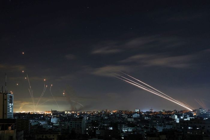 Israel's Iron Dome missile defence system (L) intercepts rockets (R) fired by the Hamas movement from Gaza city towards Israel early on May 16, 2021. 