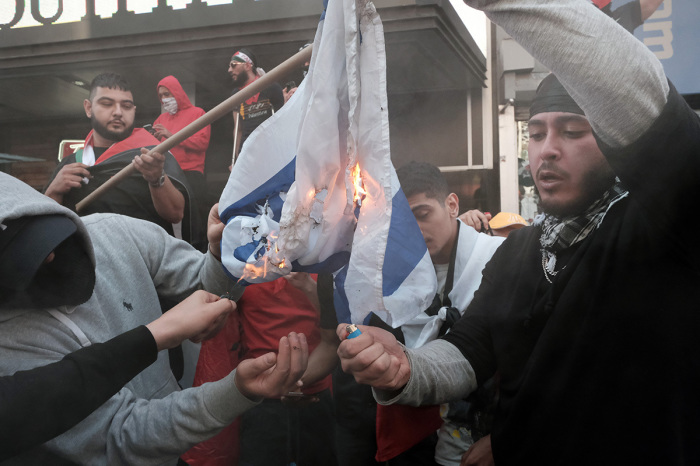 Pro-Palestinian protesters burn the Israeli flag as they face off with a group of Israel supporters and police in a violent clash in Times Square on May 20, 2021, in New York City. Despite an announcement of a cease fire between Israel and Gaza militants, dozens of supporters of both sides of the conflict fought in the streets of Times Square. Dozens were arrested and detained by police before they were dispersed out of the square. 