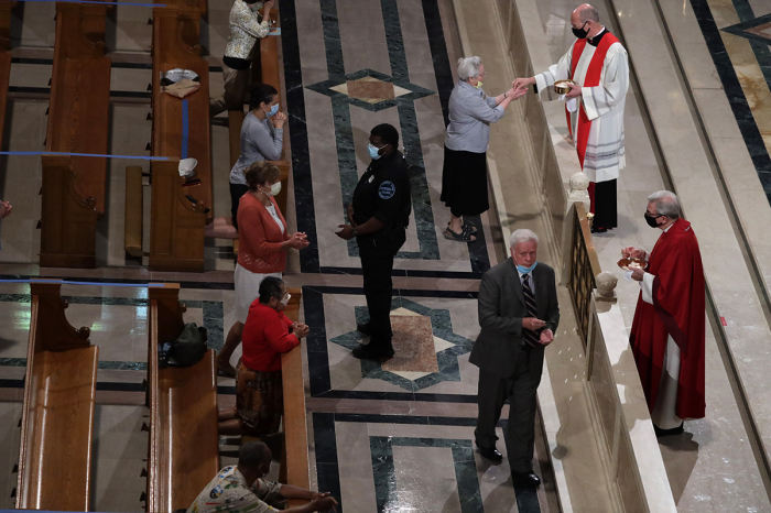Members of the congregation take part in a communion with social distancing during a mass at the Basilica of the National Shrine of the Immaculate Conception June 22, 2020 in Washington, D.C. The government of District of Columbia has begun phase two of reopening due to the COVID-19 pandemic, with houses of worship resuming at maximum of 50% capacity, and no more than 100 people. 