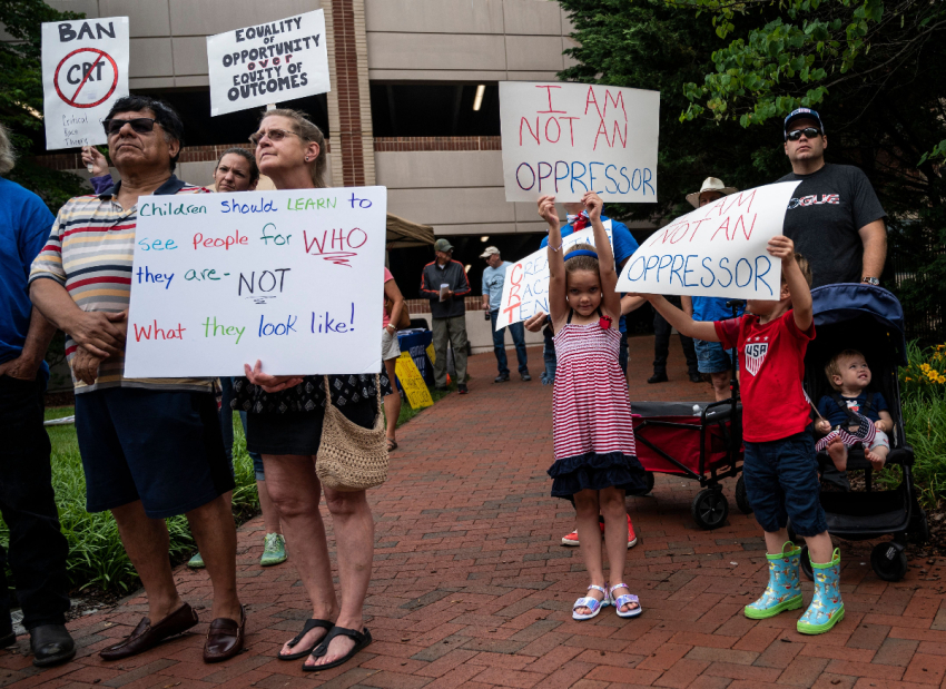 People hold up signs during a rally against "critical race theory" (CRT) being taught in schools at the Loudoun County Government center in Leesburg, Virginia on June 12, 2021. 