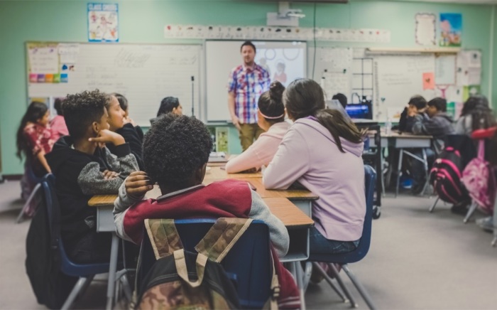 Students listen to a teacher in a classroom. 