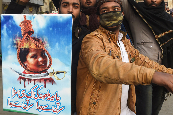 Pakistani Islamists hold a poster displaying the portrait of Asia Bibi, a Christian Pakistani woman accused of blasphemy, during a protest against the Supreme Court decision on Bibi's case in Lahore on February 1, 2019. As Islamist extremists announced fresh protests demanding her execution, officials said she was free to go abroad, with speculation rampant that she will seek asylum in Europe or North America. 