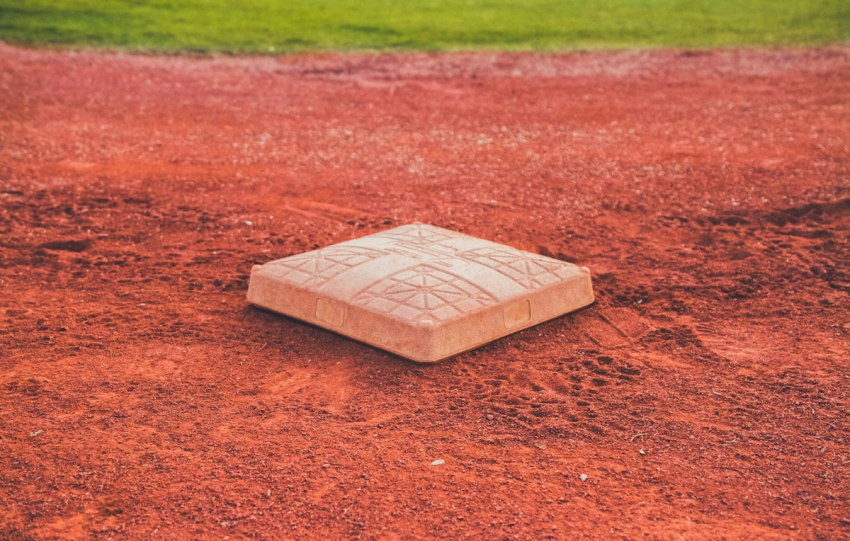 Second base lies on the dirt of a baseball field.