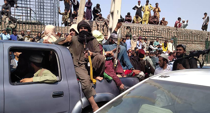 Taliban fighters sit on a vehicle along the street in Jalalabad province on August 15, 2021. 