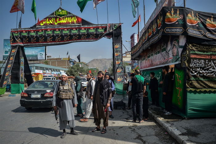 Taliban fighters stand guard near a makeshift tent where the Shiite Muslims distribute sherbet to people during the Ashura procession which is held to mark the death of Imam Hussein, the grandson of Prophet Mohammad, along a road in Kabul on August 19, 2021, amid the Taliban's military takeover of Afghanistan. 