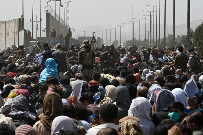 Afghans gather on a roadside near the military part of the airport in Kabul on August 20, 2021, hoping to flee from the country after the Taliban's military takeover of Afghanistan. 