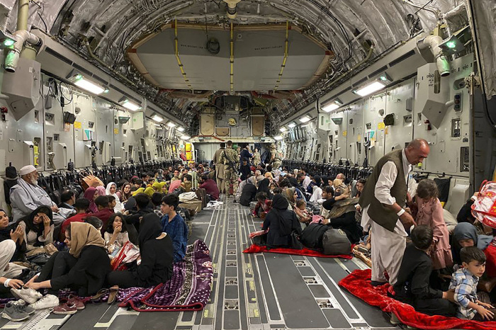 Afghan people sit inside a U.S. military aircraft to leave Afghanistan, at the military airport in Kabul on August 19, 2021, after Taliban's takeover of Afghanistan. 