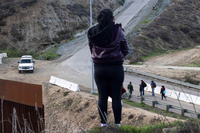 Berta Mejia, a migrant from Honduras, watches her husband and stepson and other Central American migrants surrender to the border patrol after they crossed the border fence from Tijuana in Mexico to San Diego County in the U.S., as seen from Tijuana, Baja California State, Mexico, on December 27, 2018. 