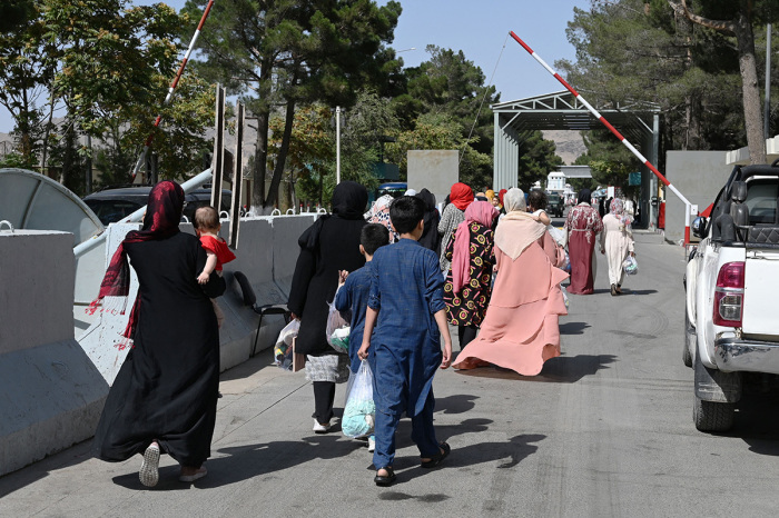 Afghans, hoping to leave Afghanistan, walk through the main entrance gate of Kabul airport in Kabul on August 28, 2021, following the Taliban stunning military takeover of Afghanistan. 