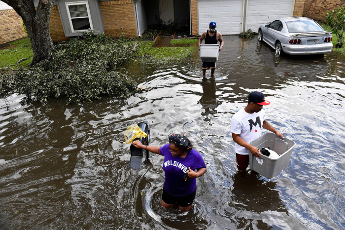 Darrin Heisser (C) evacuates from his flooded home with his dog Sonny and the help of daughter Darion Heisser (L) and Troy Gerard (R) as they wade into a high water truck volunteering to evacuate people from flooded homes in LaPlace, Louisiana on August 30, 2021, in the aftermath of Hurricane Ida. - Rescuers on Monday combed through the 'catastrophic' damage Hurricane Ida did to Louisiana, a day after the fierce storm killed at least two people, stranded others in rising floodwaters and sheared the roofs off homes. 