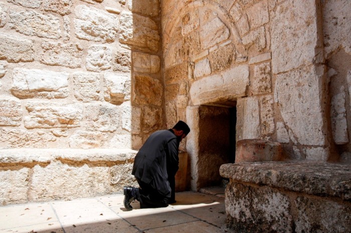 An Orthodox Christian priest prays at the entrance of the Church of the Nativity in the biblical West Bank city of Bethlehem on April 18, 2020, while the church is closed due to a lockdown imposed to stem the COVID-19 coronavirus pandemic. 