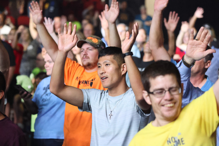 Attendees raise their hands in worship in Des Moines, Iowa, at the Will Graham Celebration event on Sunday, Oct. 3 2021.