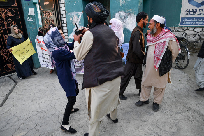 A woman protestor scuffles with a member of the Taliban during a demonstration outside a school in Kabul on September 30, 2021. 