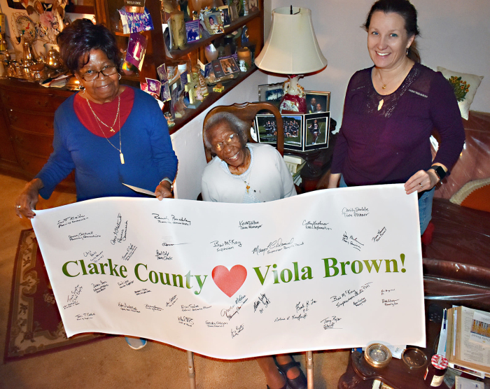 Clarke County loves Viola Brown! When Viola Brown celebrated her 108th Christmas in 2019, she was surrounded by love in her Josephine Street home where Berryville District Supervisor Mary Daniel (R) delivered a gift signed by county and town officials. Brown’s daughter Vonceil Hill holds the banner at left.