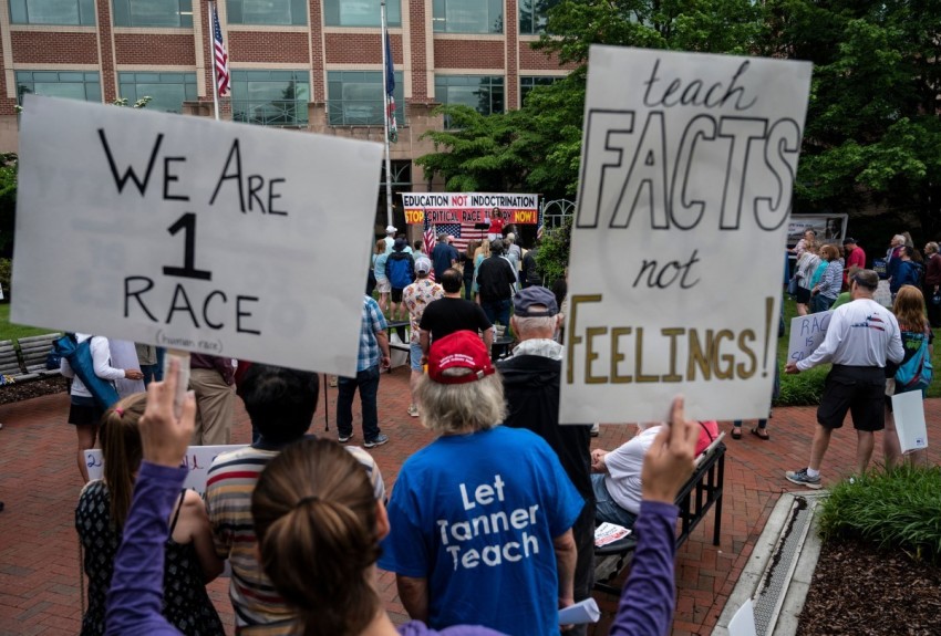 People hold up signs during a rally against
