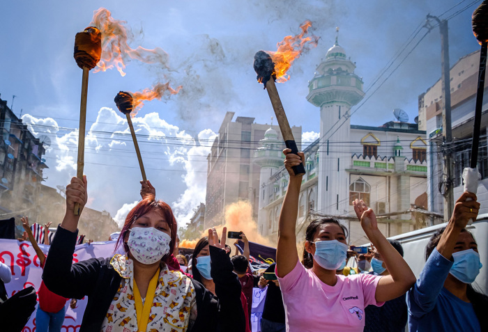 Women carry burning torches as they march during a demonstration against the military coup in Yangon on July 14, 2021. 