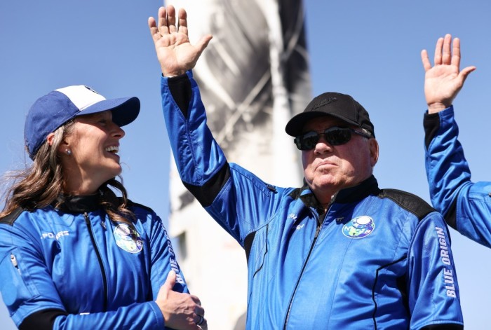 Blue Origins vice president of mission and flight operations Audrey Powers (L) looks on as Star Trek actor William Shatner waves during a media availability on the landing pad of Blue Origin’s New Shepard after they flew into space on October 13, 2021 near Van Horn, Texas. Shatner became the oldest person to fly into space on the ten minute flight. They flew aboard mission NS-18, the second human spaceflight for the company which is owned by Amazon founder Jeff Bezos.