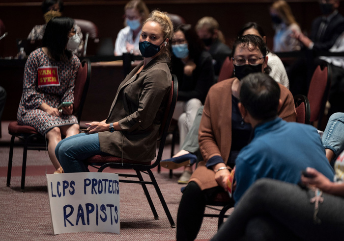 A woman sits with her sign during a Loudoun County Public Schools (LCPS) board meeting in Ashburn, Virginia, on October 12, 2021.