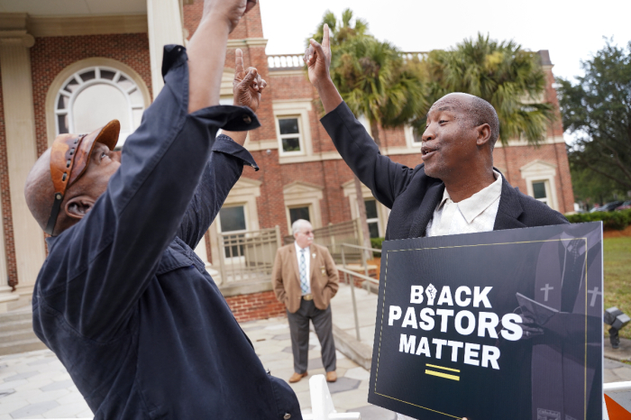 Rev. Siegfried Darcell White (R) points the sky at the Glynn County Courthouse before a court session in the Ahmaud Arbery murder trial on November 18, 2021 in Brunswick, Georgia. 
