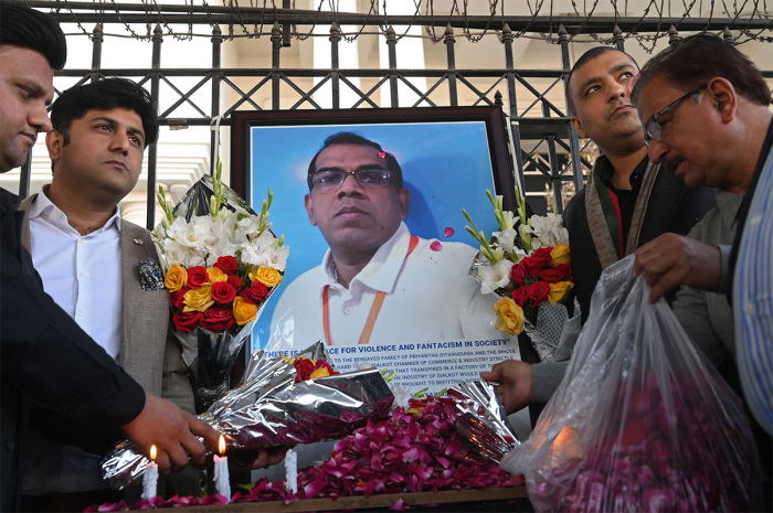 Pakistani industrialists pay tribute beside a photograph of late Sri Lankan factory manager, in Sialkot on December 4, 2021, after he was beaten to death and set ablaze by a mob who accused him of blasphemy, officials said on December 4. 