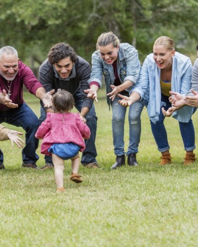 A multi-generation c family standing in the park together. 