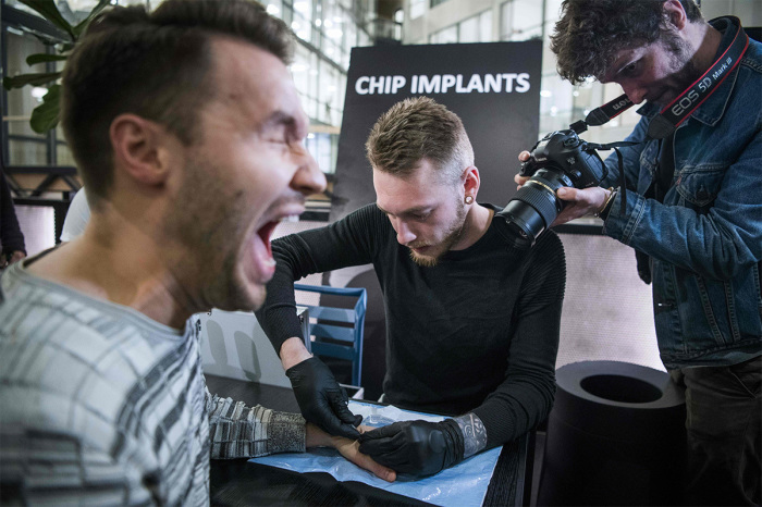 A man reacts as he gets a chip implant in his hand during a chip implant event in Epicenter, a technological hub in Stockholm on January 18, 2018. An electronic implant inserted under the skin to replace keys, business cards and train tickets: in Sweden, it is a reality for some thousands who are indifferent to the potential dangers of the intrusion of technology. 