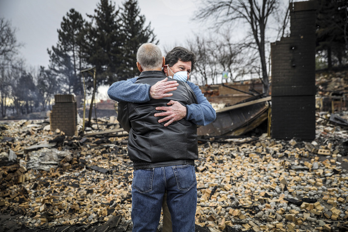 Neighbors Louie Delaware (L) and Roy Nelson hug in the rubble of Delaware's home in the aftermath of the Marshall Fire on December 31, 2021, in Louisville, Colorado. Delaware's home was leveled in the fire while Nelson's home right across the street was spared. The fast-moving wind-driven fire that erupted Thursday in multiple spots around Boulder County forced some 30,000 people out of their residences and may have destroyed as many as 1,000 homes. 