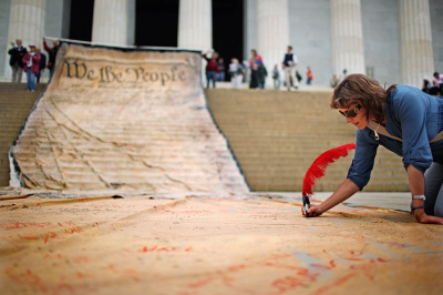 A woman signs a giant banner printed with the Preamble to the United States Constitution during a demonstration against the Supreme Court's Citizens United ruling at the Lincoln Memorial on the National Mall October 20, 2010, in Washington, D.C. 