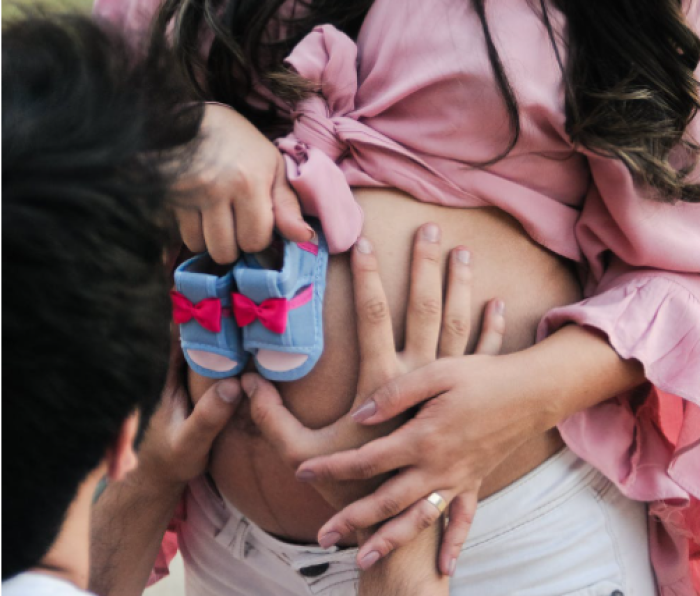 A man touches a pregnant woman's belly. 